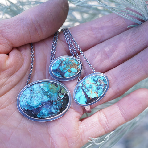 three turquoise necklaces held in the palm of a hand