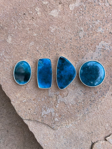 four deep blue cabochon stones of Glacierite that look like the night sky