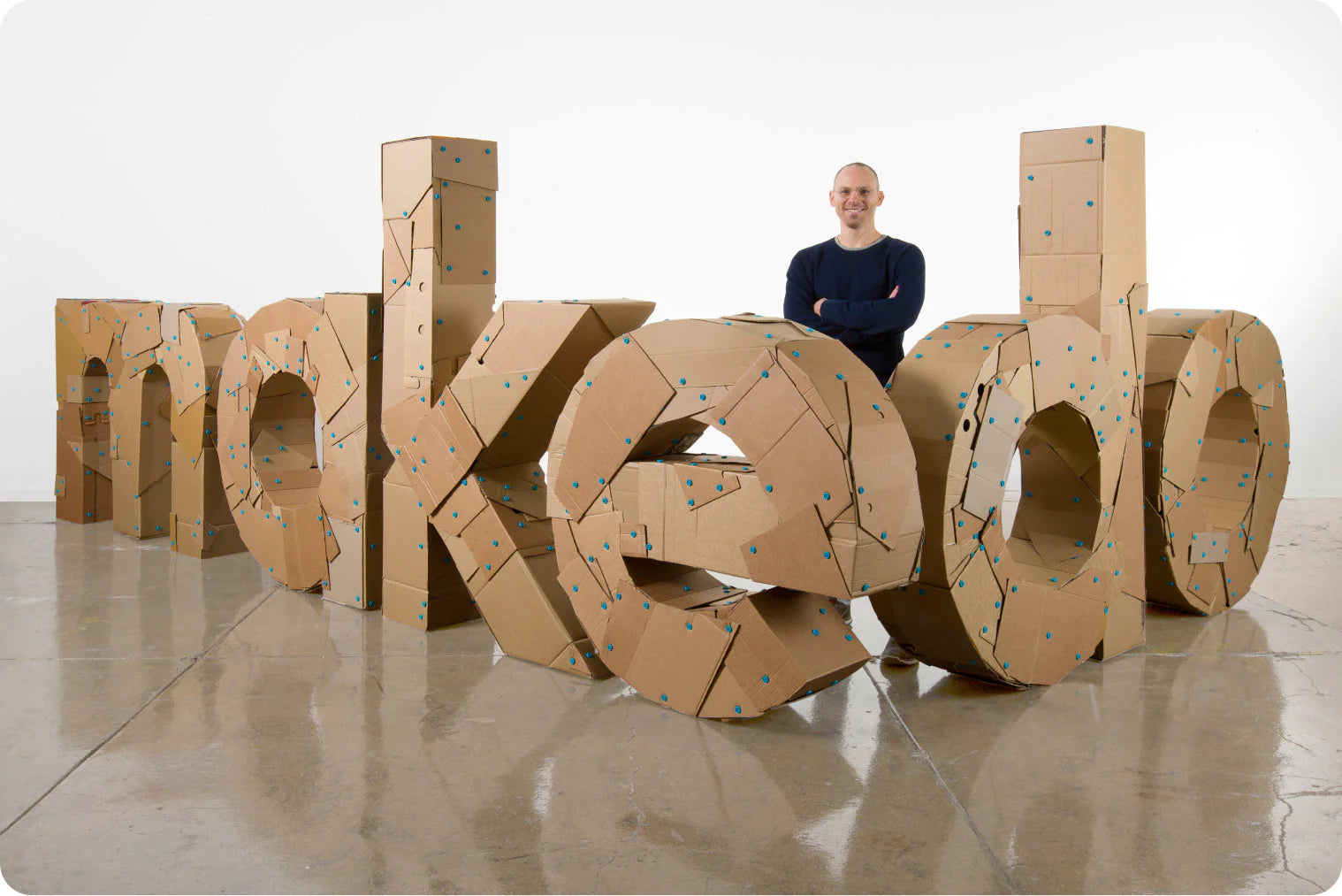 cardboard letters spelling makedo with owner of company standing behind them