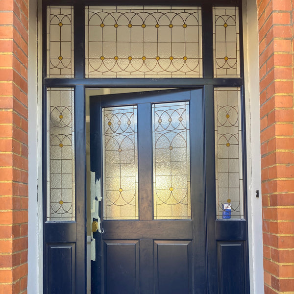 Navy fron door with clear simple stained glass with amber circles