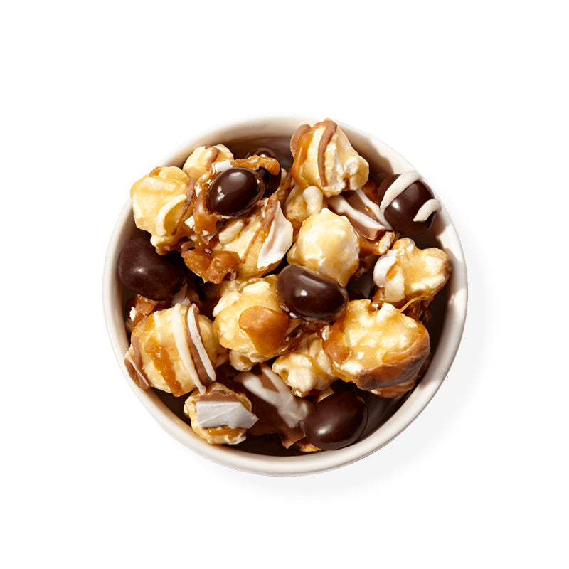 Nutty Choco Pop product, there is popcorn, almonds, cashews, and white chocolate, caramel, and chocolate drizzle on all of them