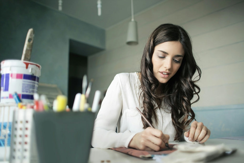 Woman sitting while holding pen