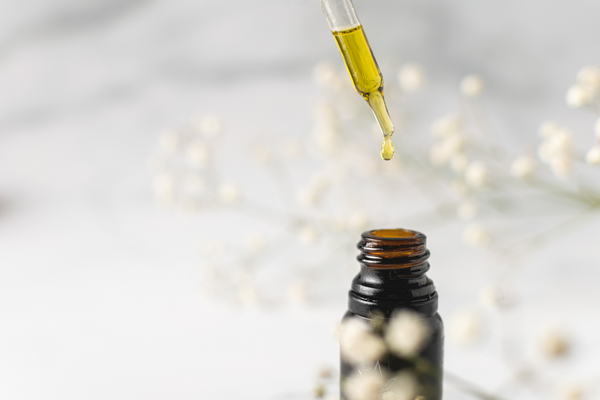 CBD oil dropper against white background with flowers