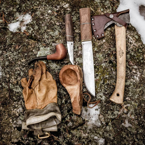 axe knife spoon in wood and gloves equipment for bushcraft and outdoor wild camping