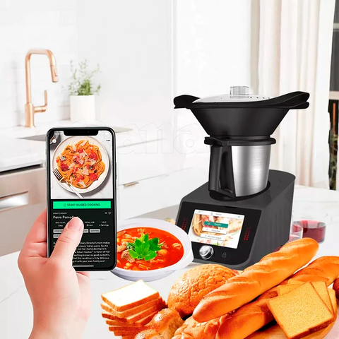 Procesador de comida proyecta en su pantalla el menú principal. En frente hay un platillo y una variedad de panes. Una mano sostiene un celular, donde se proyecta la aplicación del producto.