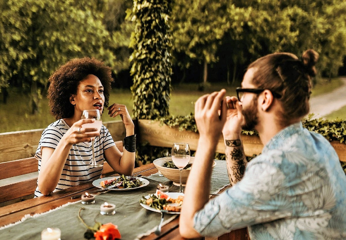 A couple sat at a table outdoors eating