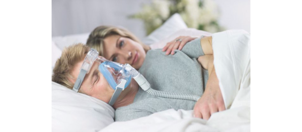 sleeping older man using CPAP with wife