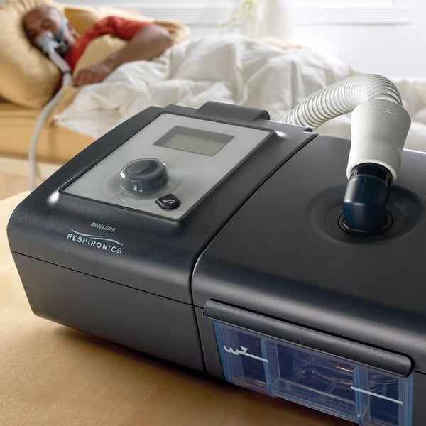 CPAP machine with sleeping man in background