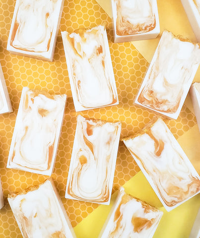 White soap bars with golden swirl design on a honeycomb background