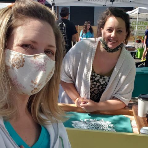 Two women smiling at a farmer's market booth