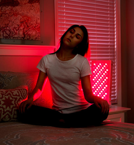 Woman using red light therapy device at home