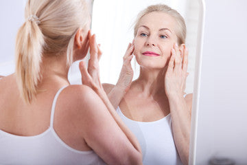 older woman looking at her face in the mirror