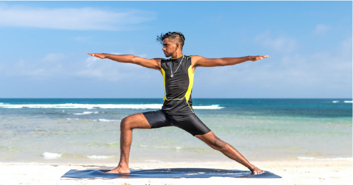 man doing yoga on the beach