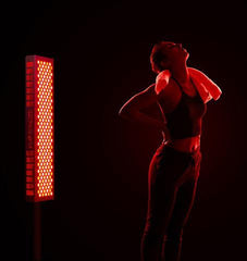 Woman Standing Next to Red Light Therapy Device