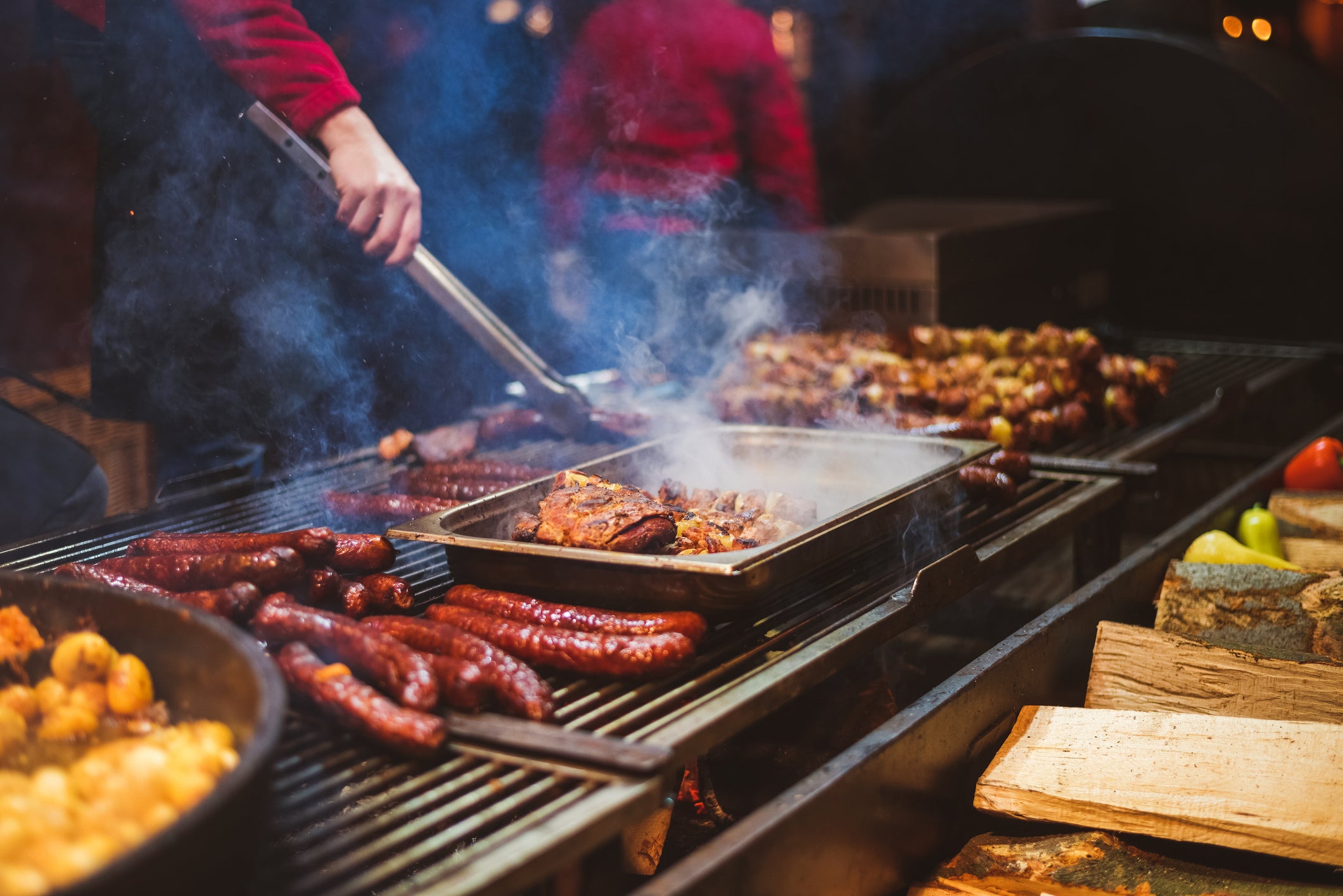 A chef working an outdoor grill for barbecuing a variety of food.