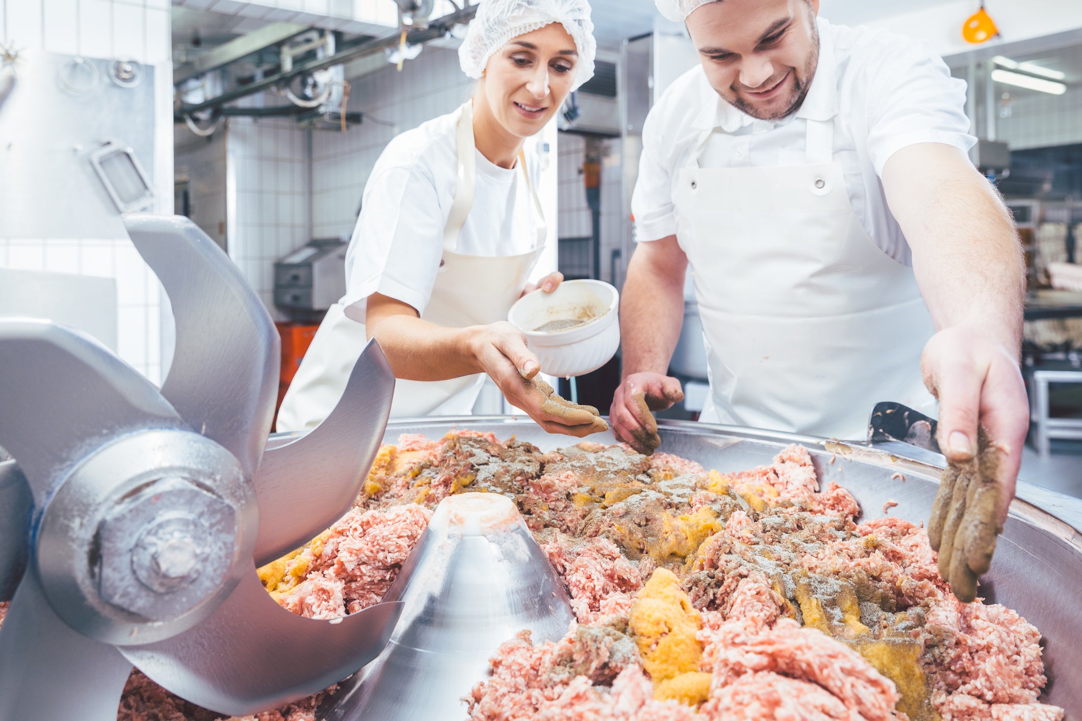 Butchers adding spices to the minced meat