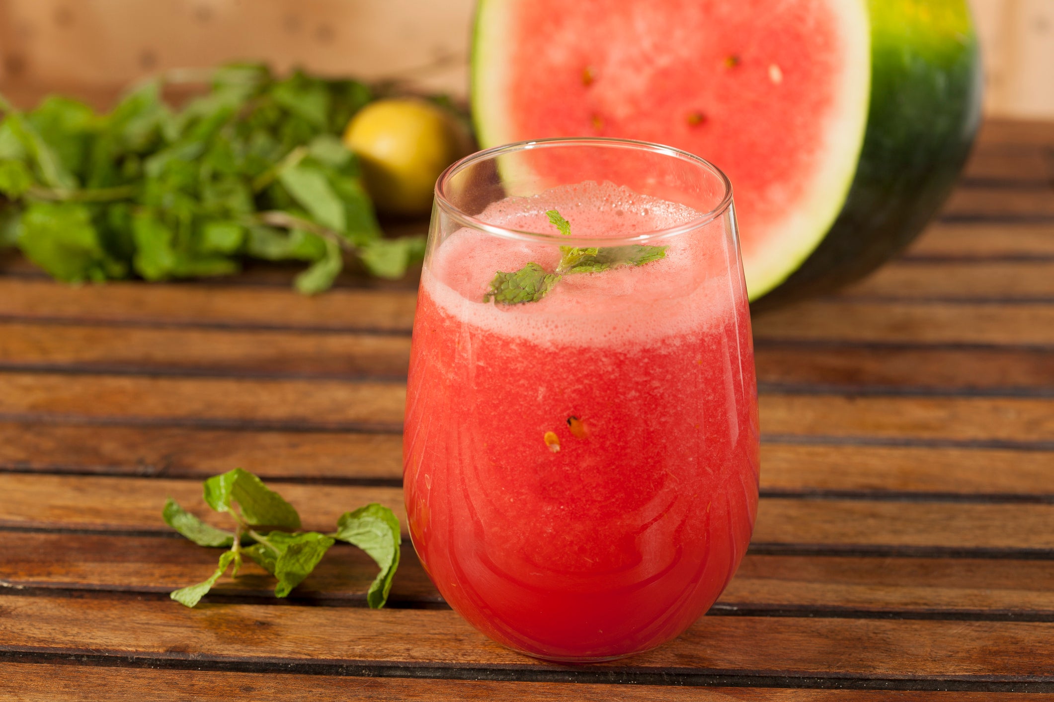 A glass of watermelon juice garnished with mint leaves
