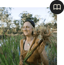 A woman stand smiling in a field of reeds