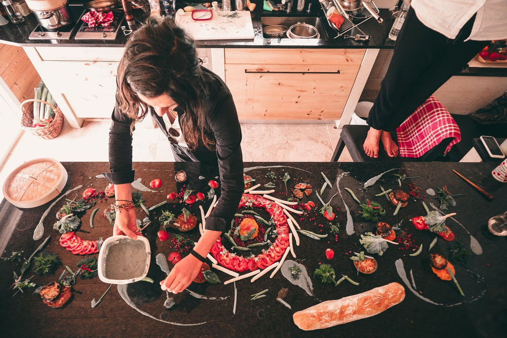 a woman prepares a gourmet spread of fruits and sauces on a counter top