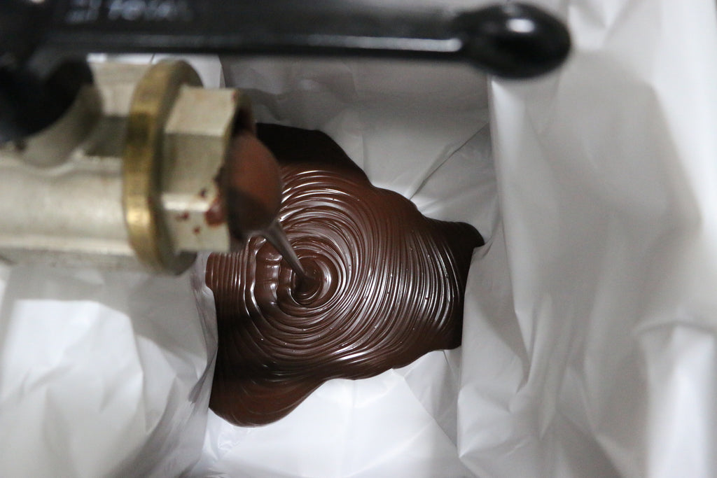 chocolate being poured from chocolate-making machine