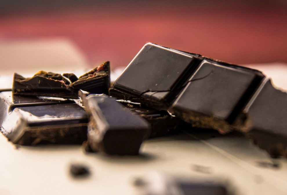 a bar of dark chocolate broken into pieces on a wooden surface