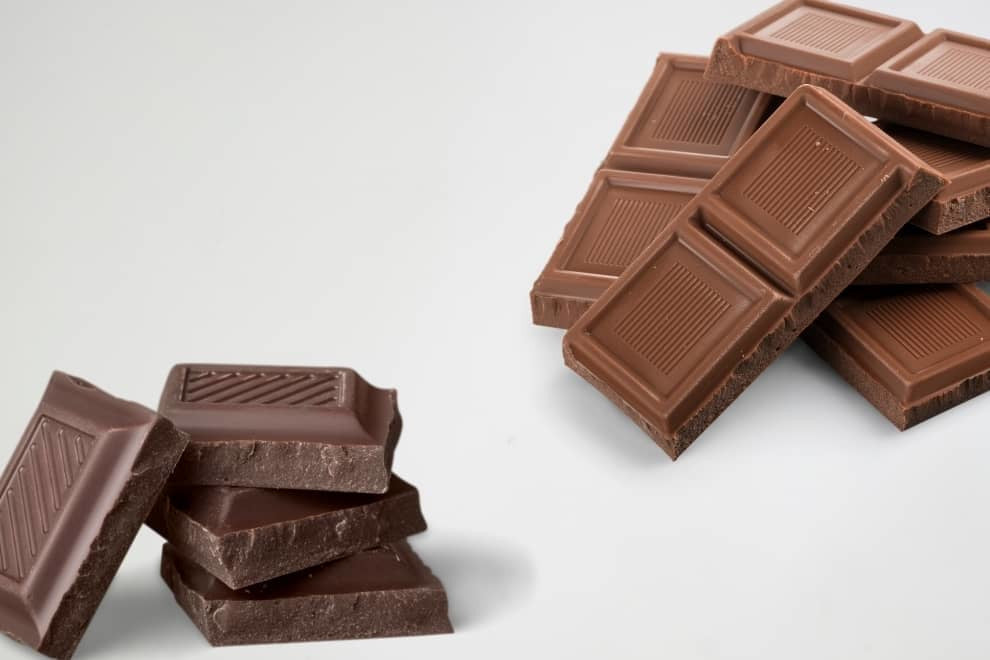 a stack of dark chocolate bars beside a stack of milk chocolate bars