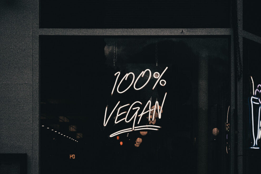 The words "100% Vegan" are written on the glass window of a store