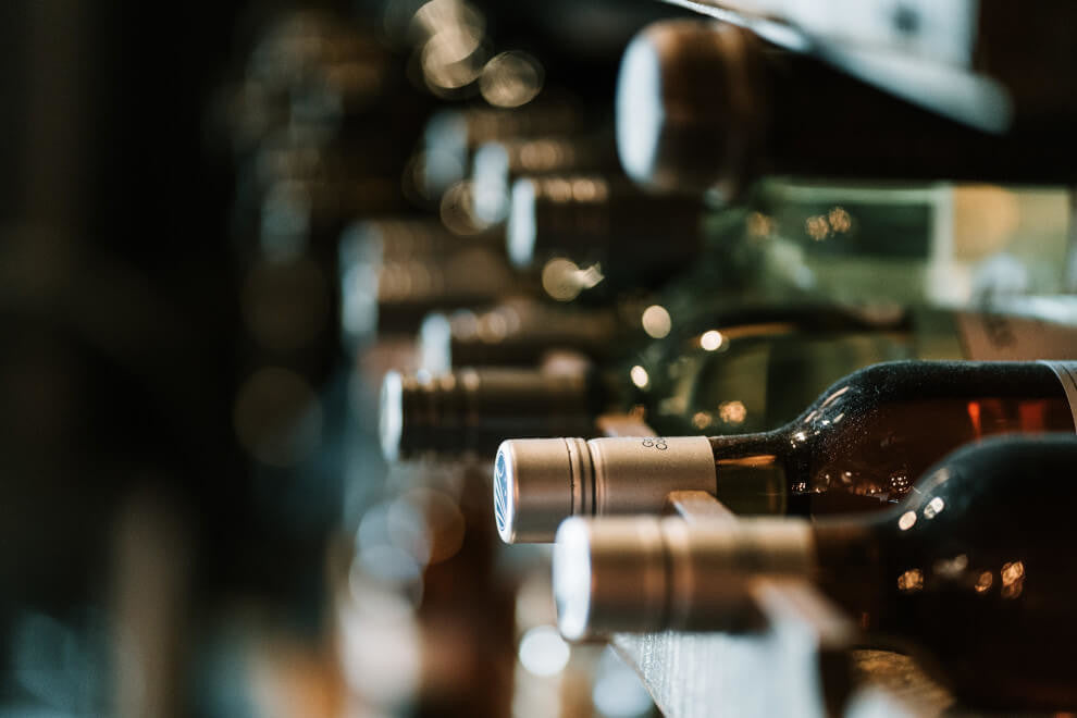 blurred close-up image of a cellar filled with bottles of wine