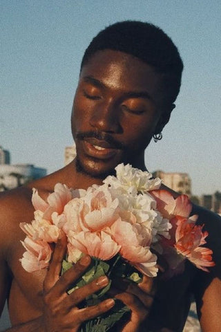 Beautiful black man with flowers and dark skin in the sunlight