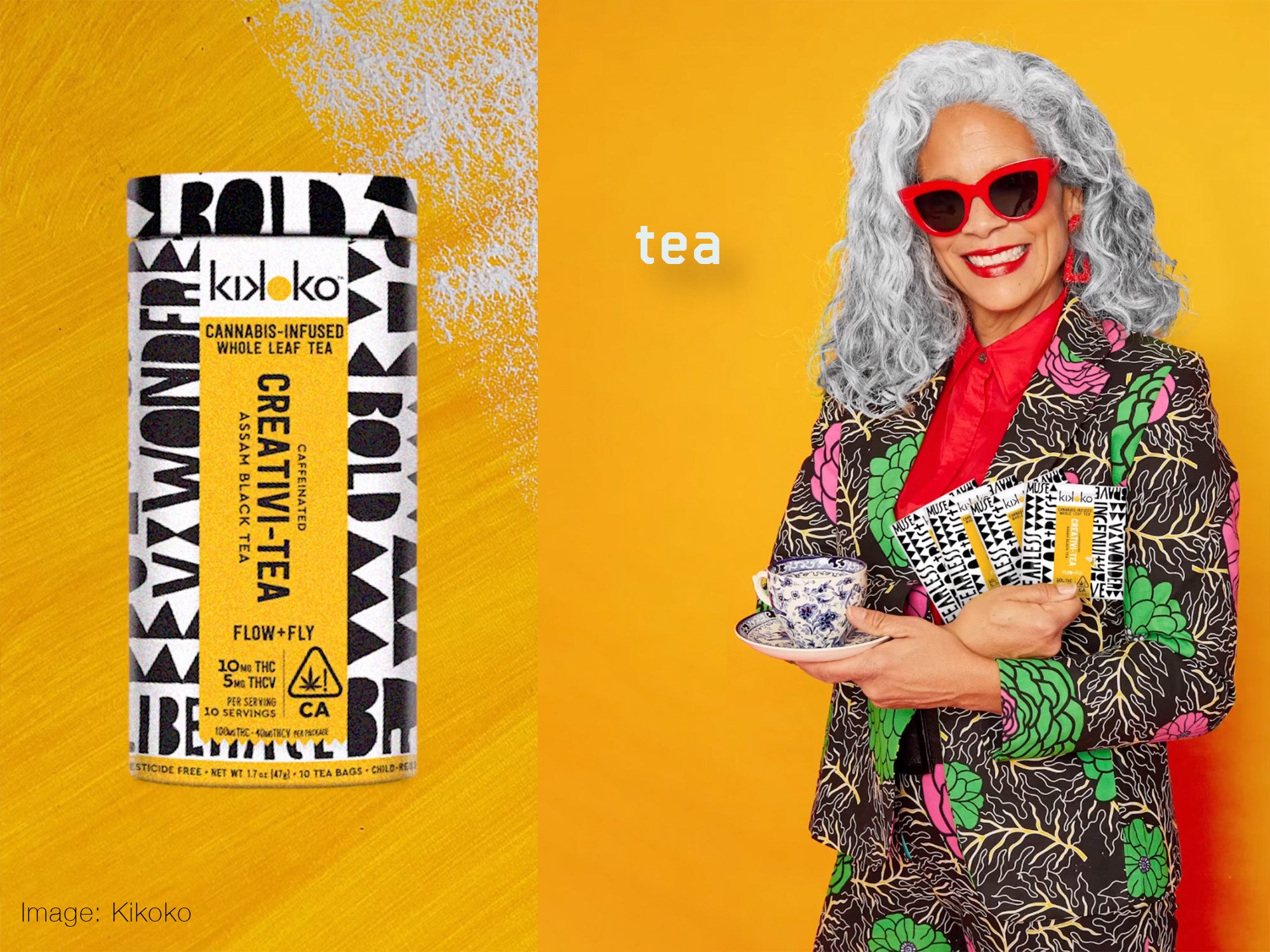 Box of tea close up on a yellow surface on the left, and on the right a woman with long white hair, red rimmed glasses, and a bright patterned suite holding several boxes of the same tea pictured on the left.