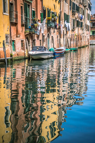 The buildings and boats of Venice reflected in the canal