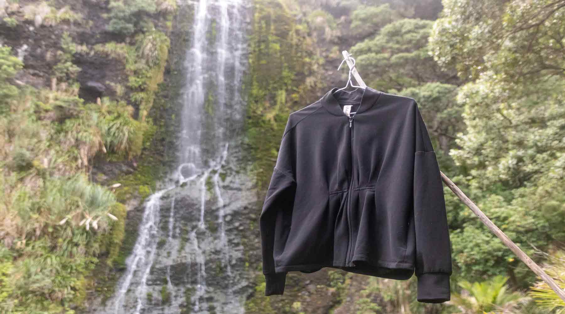 Asmuss Pleated Zip Through Sweater in front of the Karekare Falls New Zealand