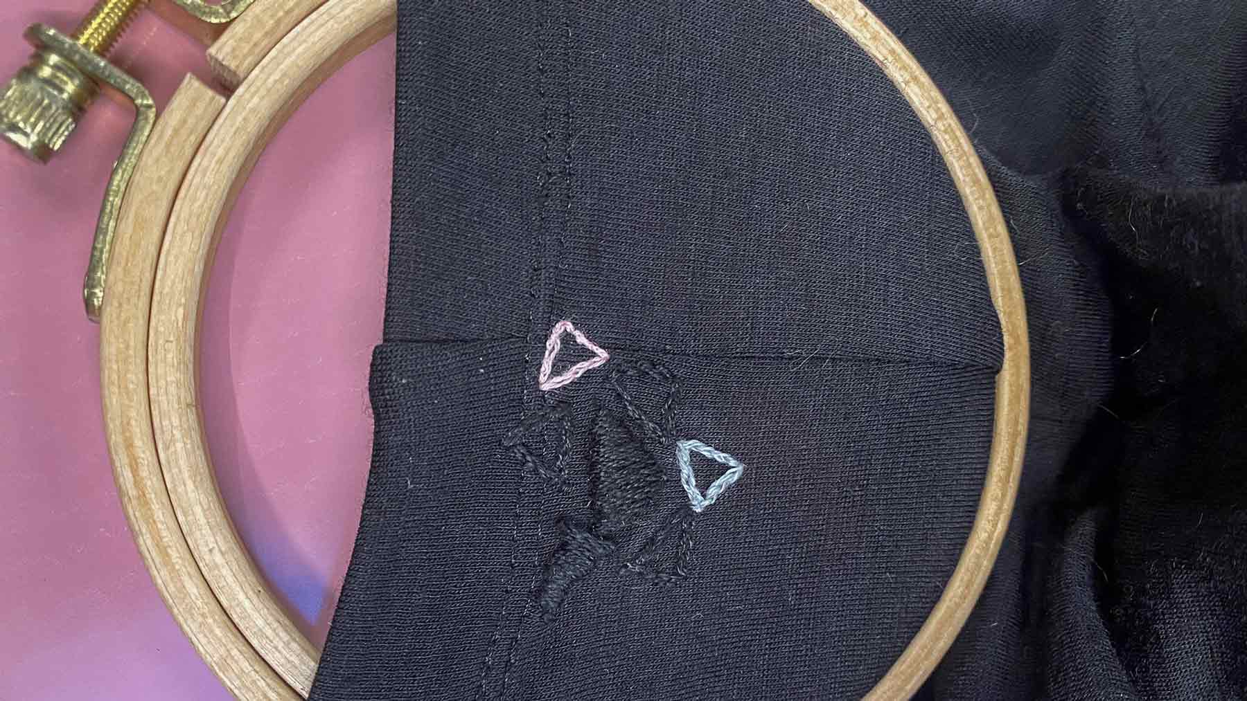 Close up of visible embroidery on a black top to mend a small hoe