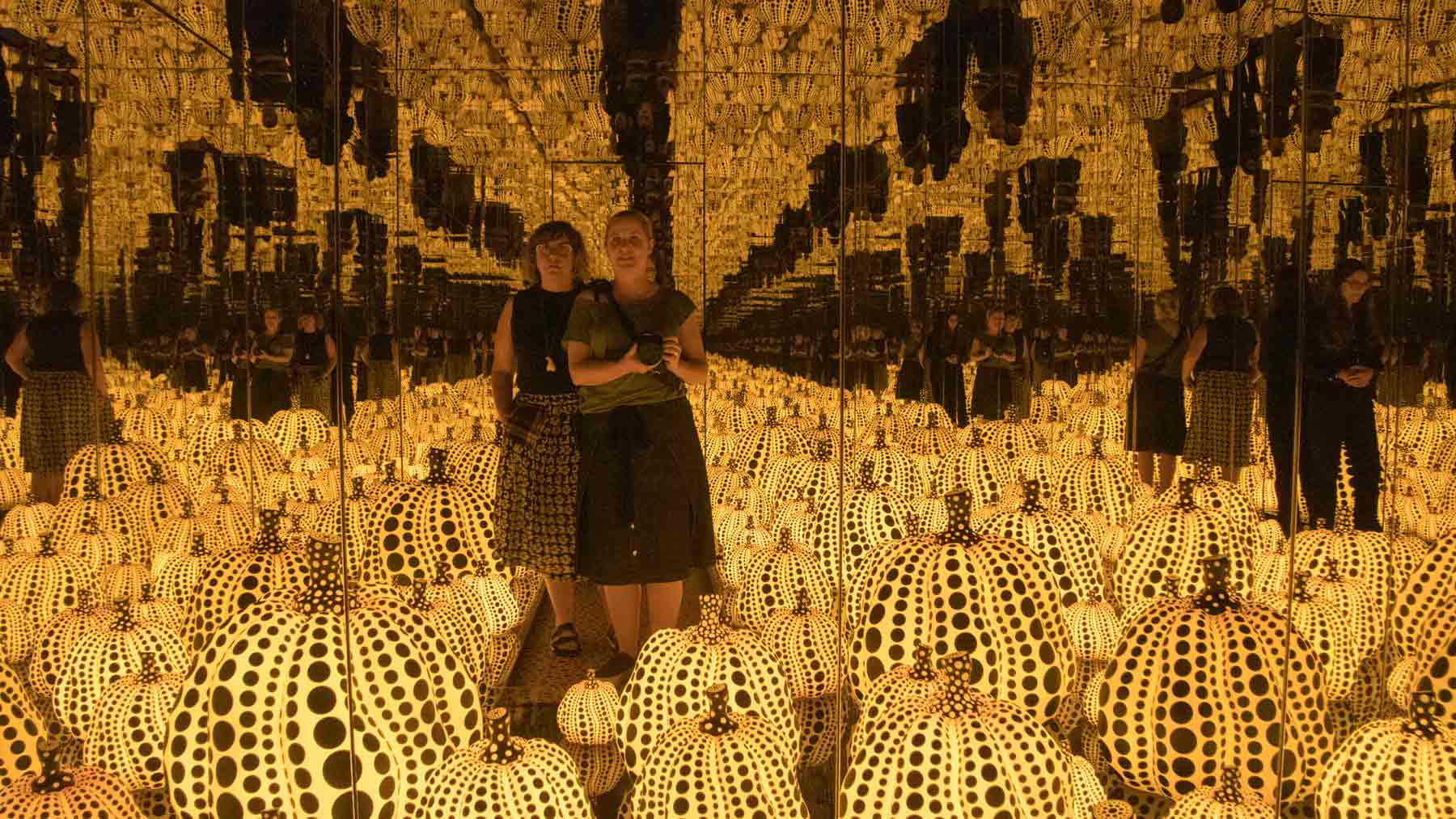 Clare and Fiona standing reflect in Yayoi Kusama's Infinity Room All the Eternal Love I Have for the Pumpkins (2016)
