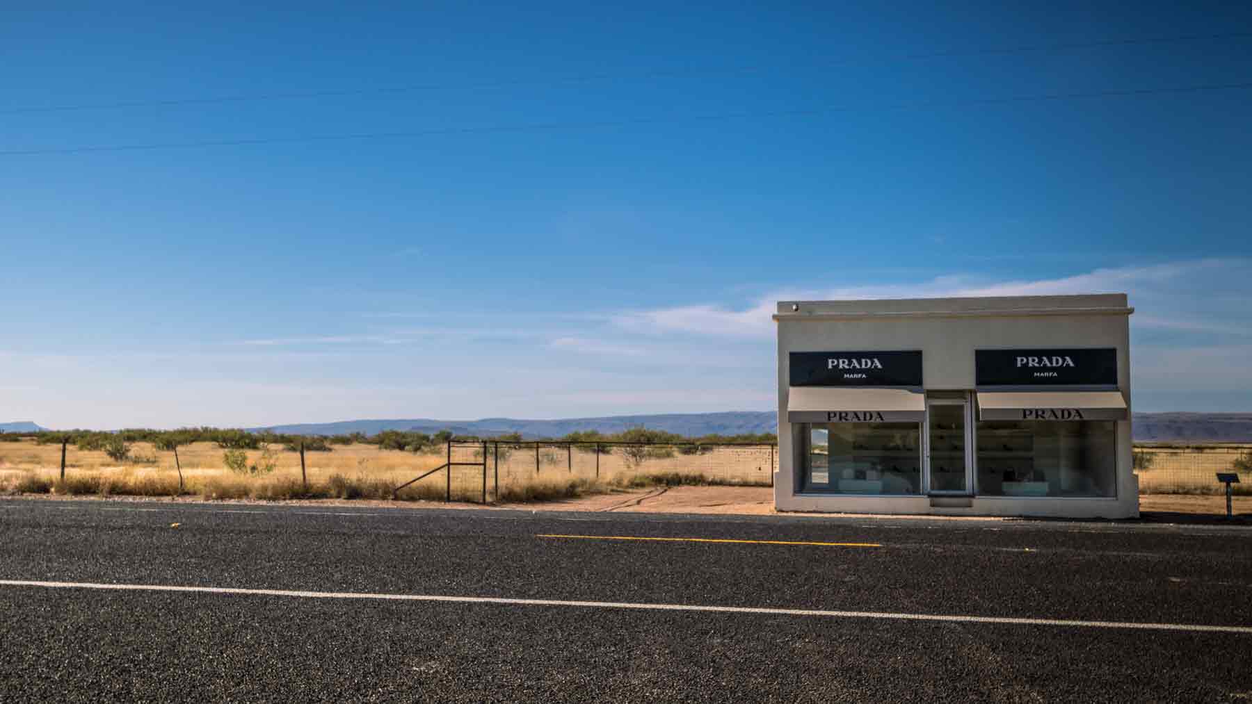 Prada Marfa art installation with road in foreground and bright blue sky in the background