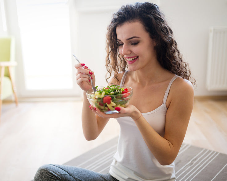 Woman eating healthy salad after working out at home
