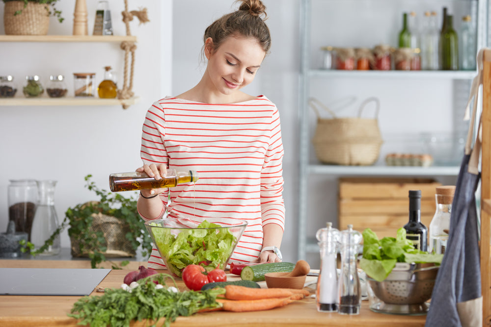 Woman adding olive oil to her healthy salad