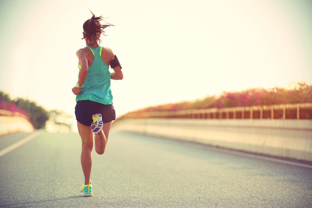 Young woman runner running on city bridge road