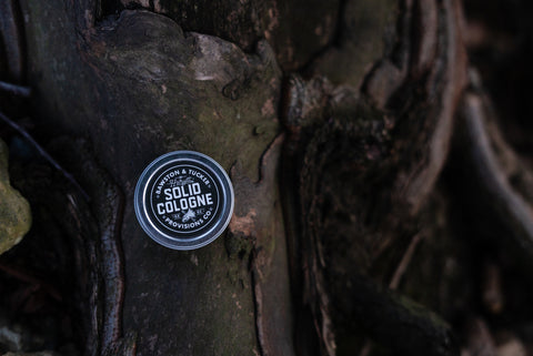 solid cologne tin sitting on a wooden branch in forest