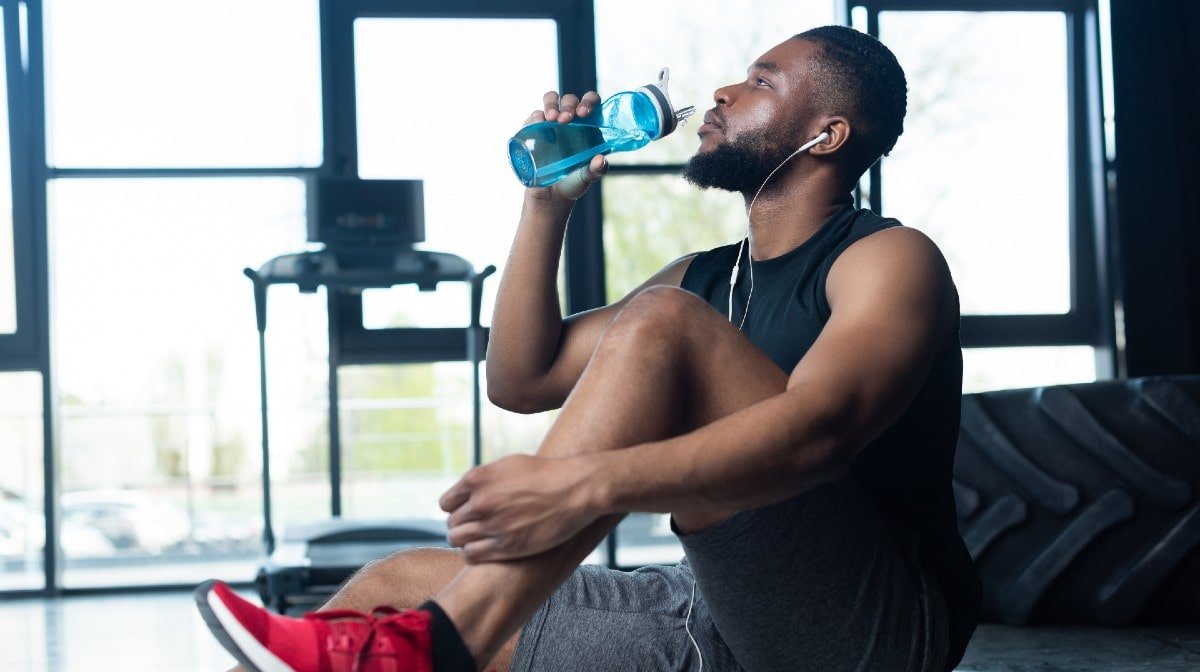 man drinking water in gym