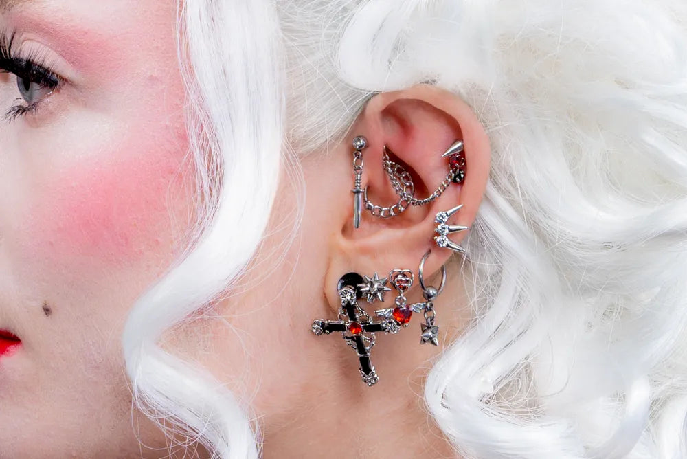 A heavily pierced ear featuring gothic maximalist piercing jewellery by Impaler Body Jewellery