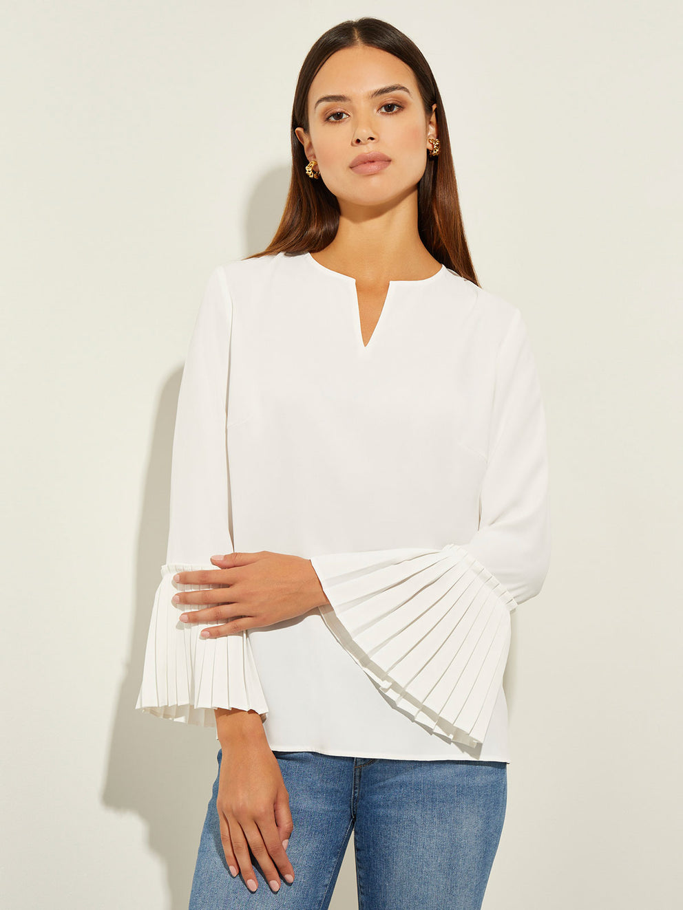 Model Wearing Gold Clip-On Earrings and the Pleated Bell Sleeve Split Neck Crepe Blouse in White