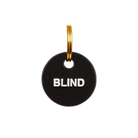 Black rubber mini charm tag with gold split ring, featuring the word 'BLIND' for visually impaired pets.