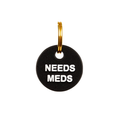 Black rubber mini charm tag with gold split ring, displaying the words 'NEEDS MEDS' for pets with specific medical needs.