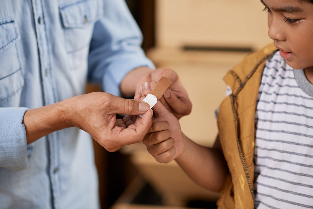 Father putting a band-aid on his son’s wound