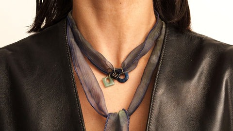 Close up photo of a woman wearing a silk necklace with charms