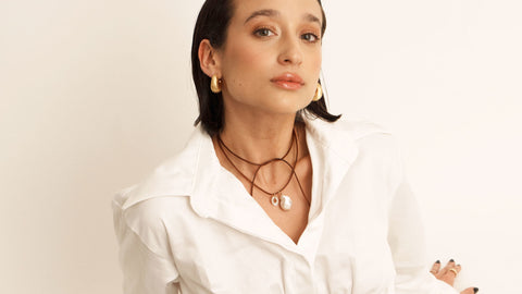 A photo of a woman wearing a leather necklace with a pearl charm 