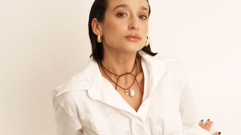 A photo of a woman wearing a leather necklace with a pearl charm