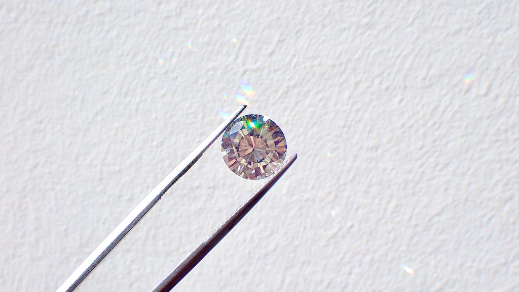 A polished diamond held by a pair of tweezers