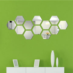 Bright green wall with hexagonal mirrored wall stickers on it.  Below is a white dresser with white items sitting on it.